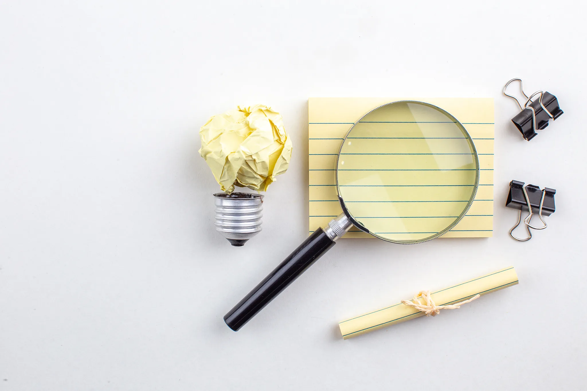 Case Studies schreiben lassen – Symbolbild mit Lupe, Notizzettel und Glühbirne als Metapher für Ideenfindung und Analyse