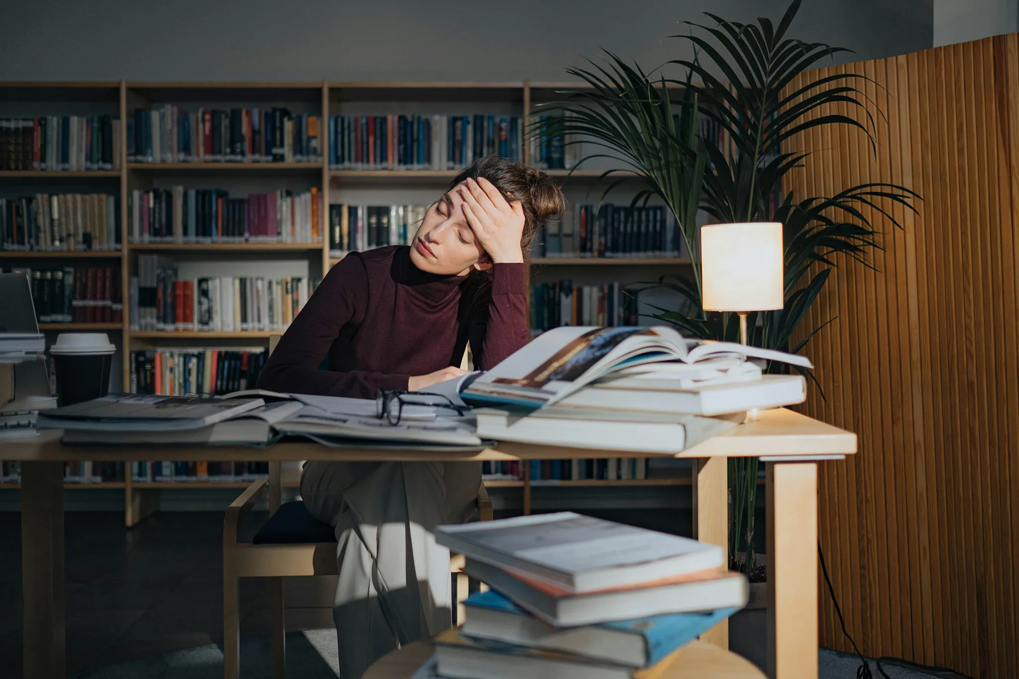 Fachartikel schreiben lassen – mit Expertise und Leichtigkeit zum Ziel Erschöpfte Frau mit Büchern am Schreibtisch – Fachartikel schreiben lassen