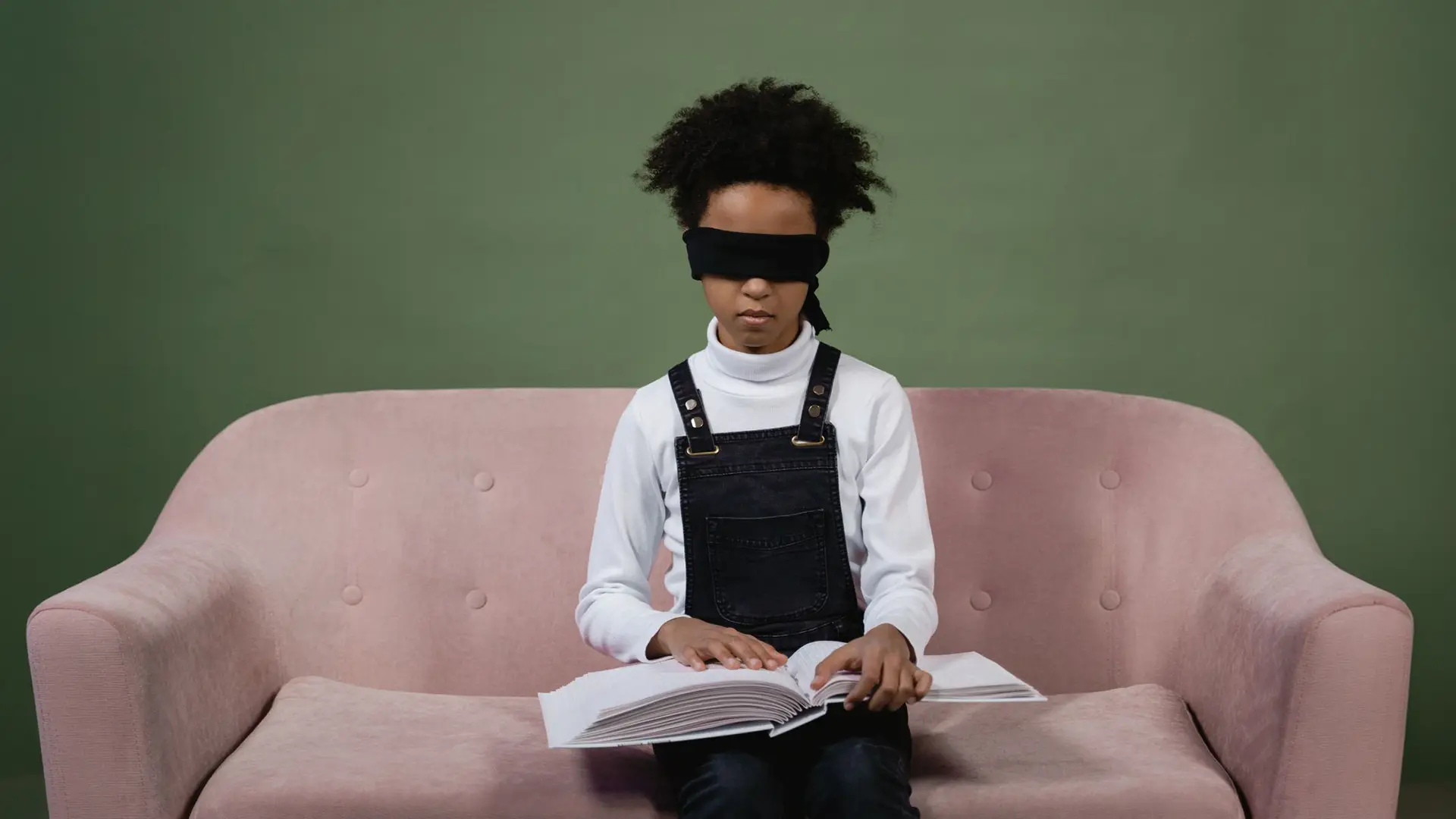  Person mit Augenbinde sitzt auf einem Sofa und hält ein aufgeschlagenes Buch – symbolisches Motiv für Buch-Lektorat