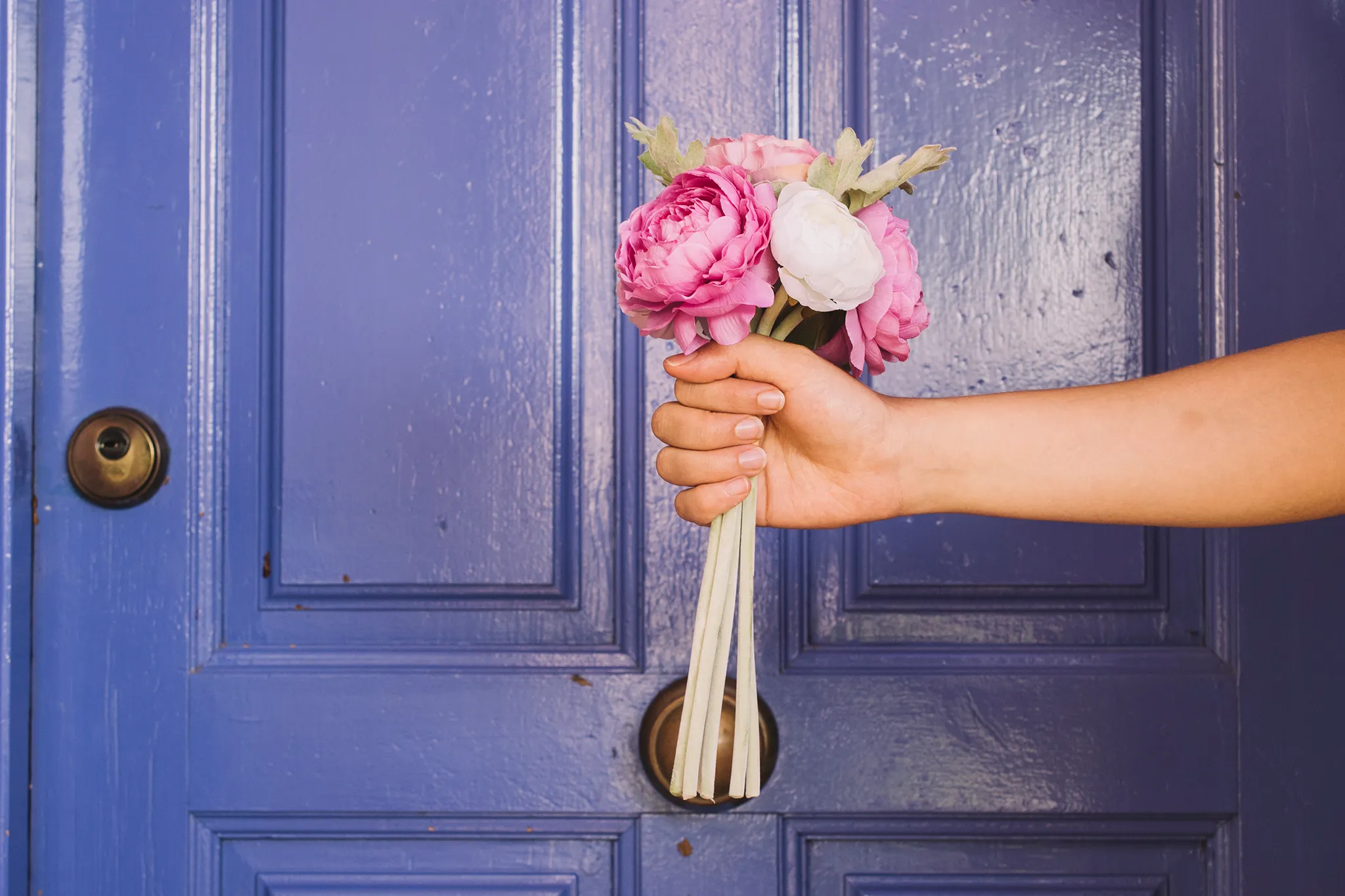Einladende Homepage – der erste Eindruck zählt Hand mit Blumenstrauß vor einer Haustür – Symbol für eine einladende Website.
