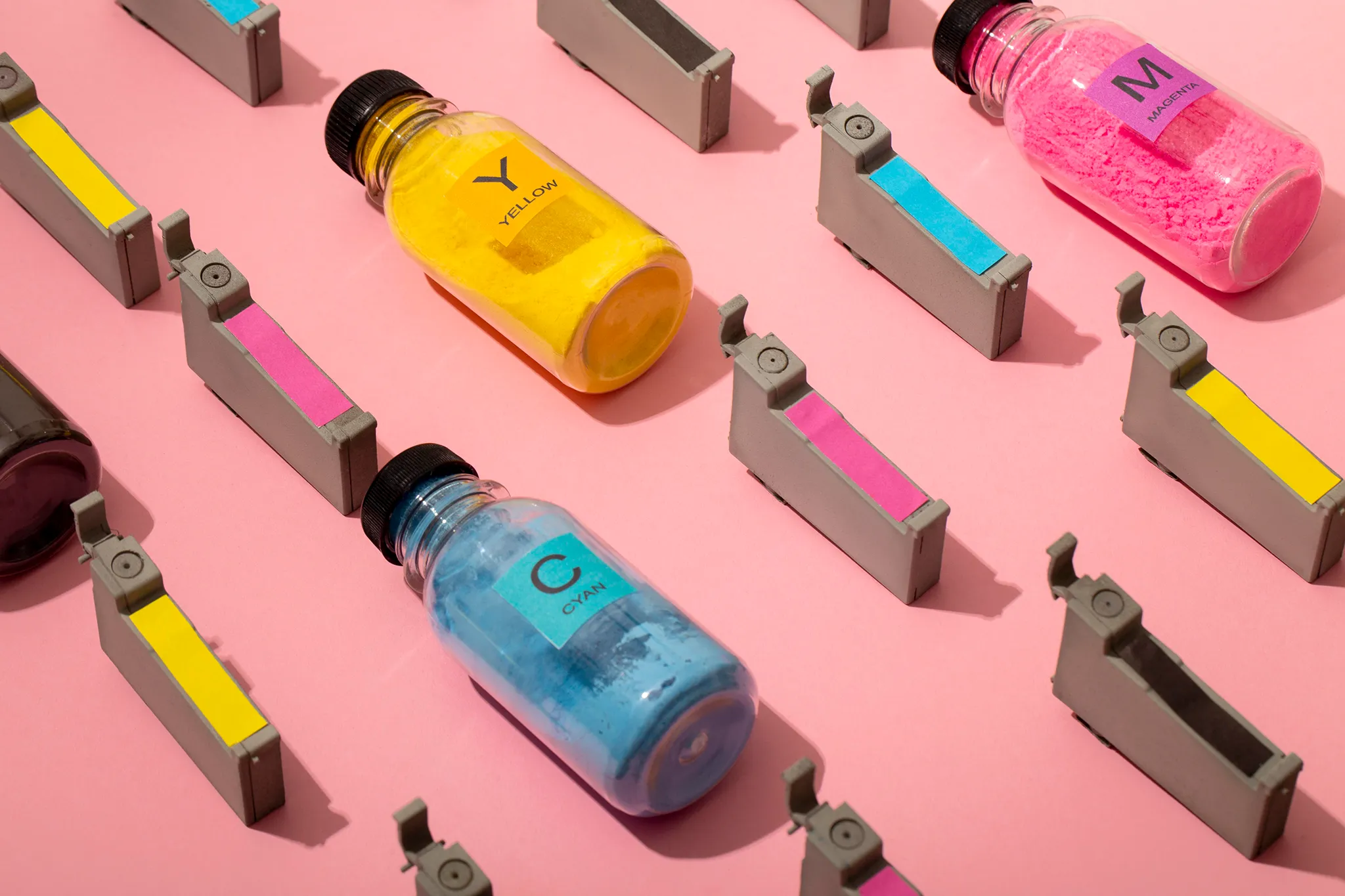 Farbpatronen und Druckerfarben auf rosa Hintergrund – Print in CMYK