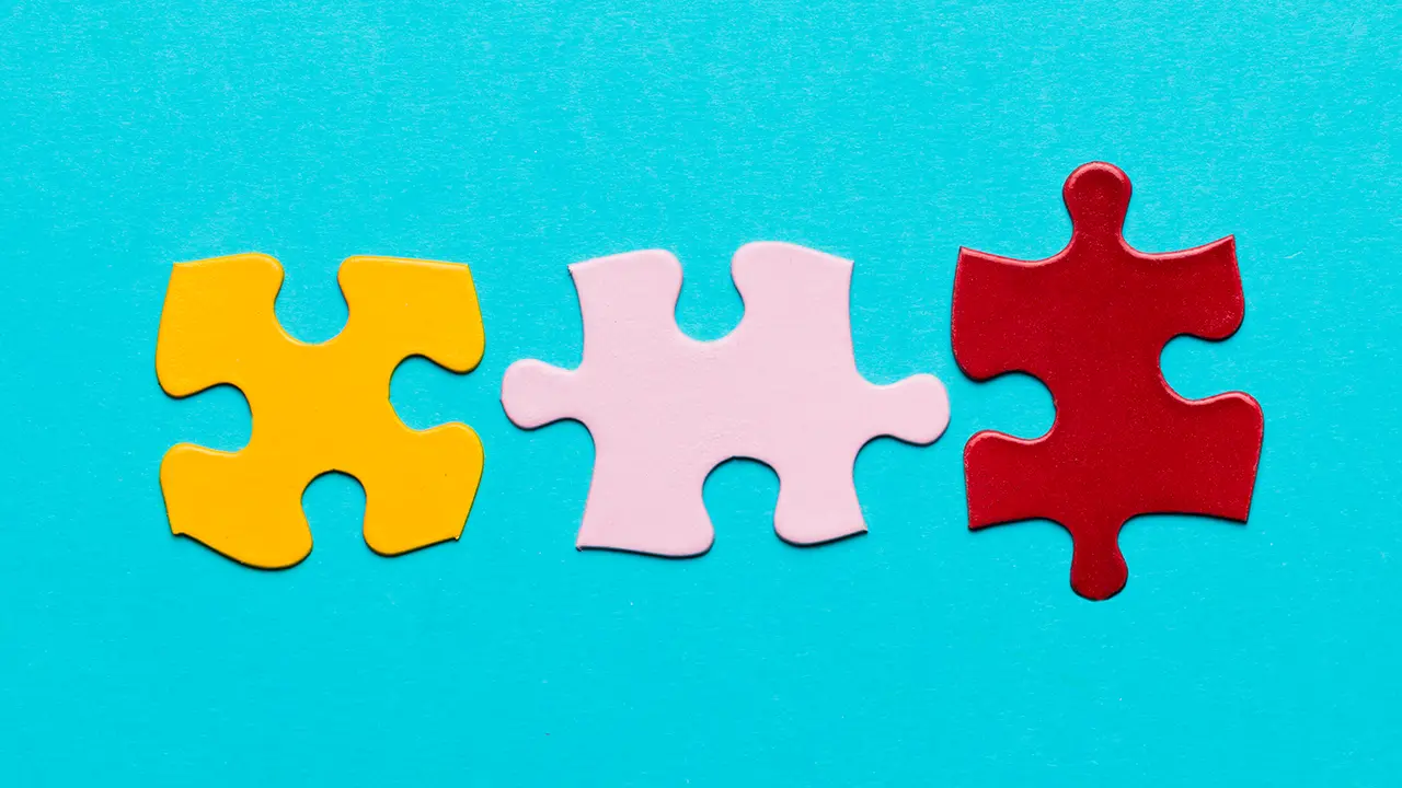Drei bunte Puzzleteile auf blauem Hintergrund, die nicht vollständig zusammenpassen