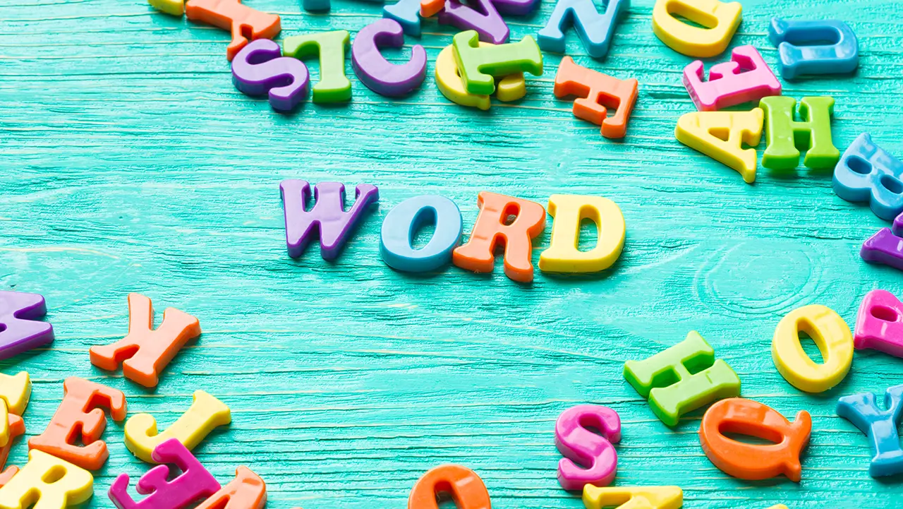 Englisch Deutsch Übersetzung – präzise, stilvoll und kulturell passend übersetzt. Bunte Buchstaben auf türkisfarbenem Holzuntergrund, die das Wort „WORD“ bilden – Symbol für Sprache und Englisch Deutsch Übersetzung.
