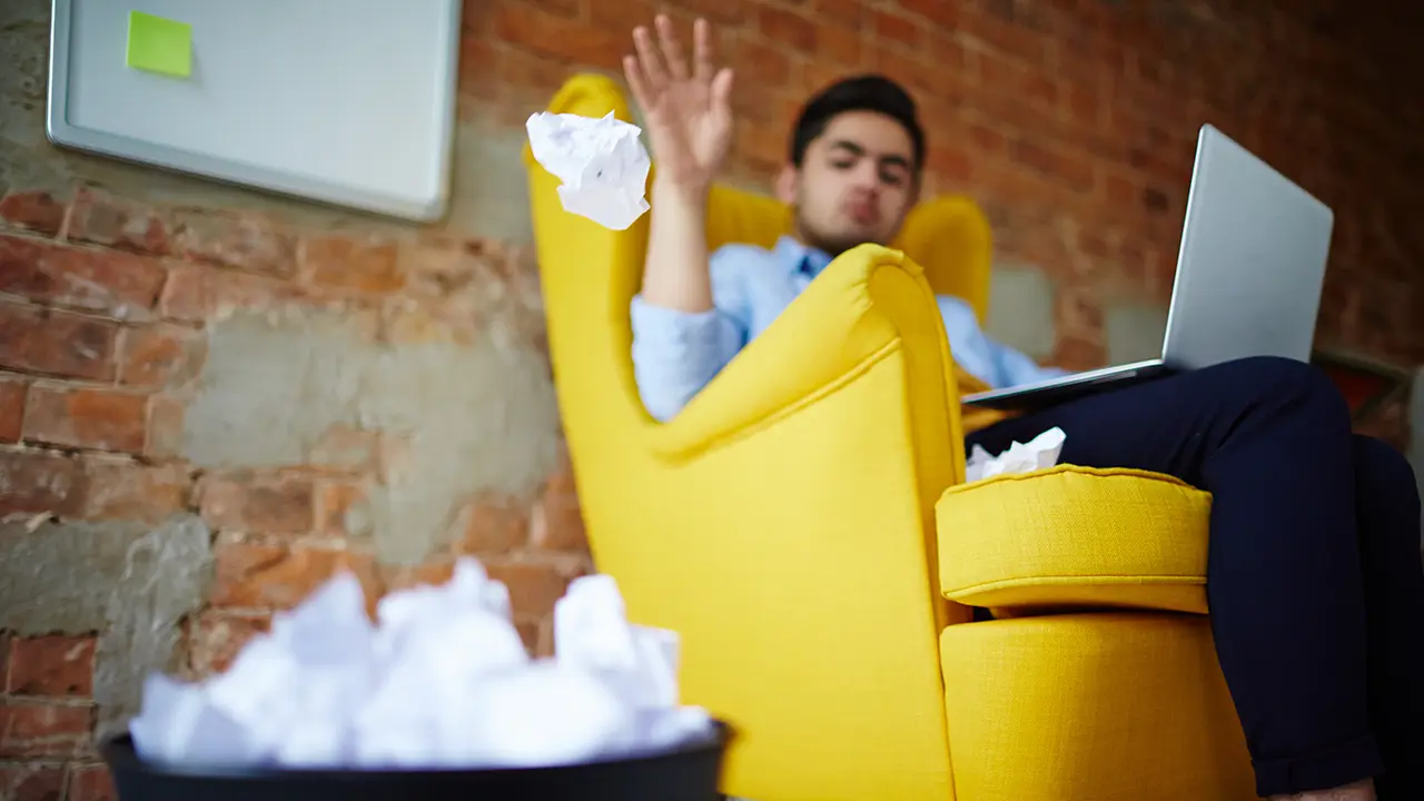 Ghostwriter bei Schreibblockade im Büro – wenn die Ideen fehlen Frustrierter Mann im Büro mit Laptop und Papieren – Symbol für Schreibblockade und die Unterstützung durch einen Ghostwriter.